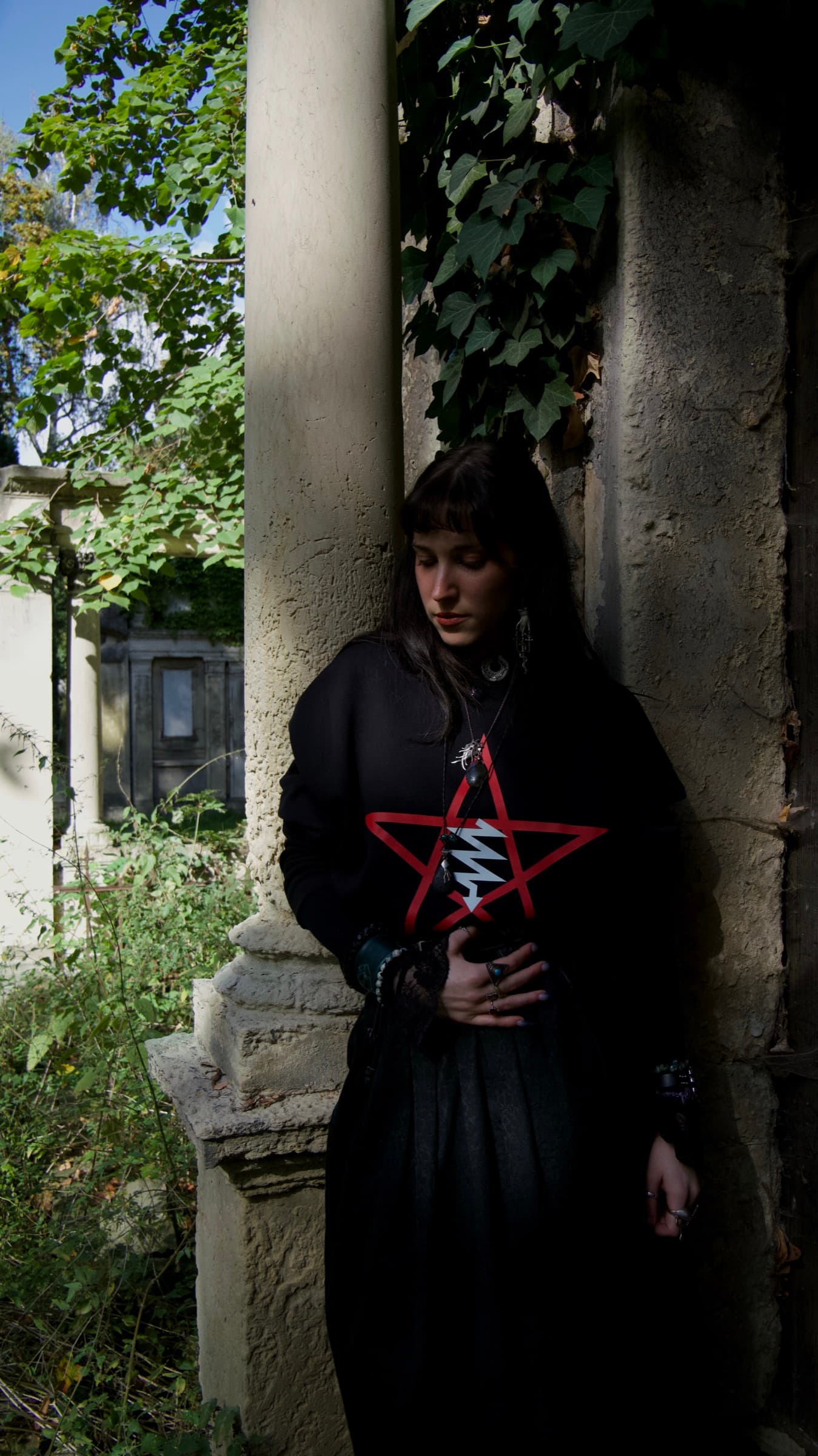 LVX sweatshirt styled with a long black skirt beside a stone column